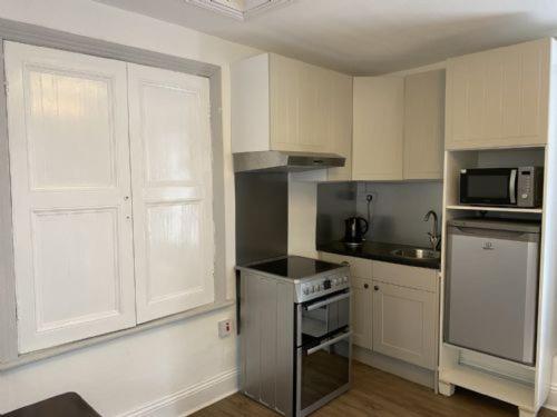 a small kitchen with a stove and a microwave at The Manager's Suite in New Mills
