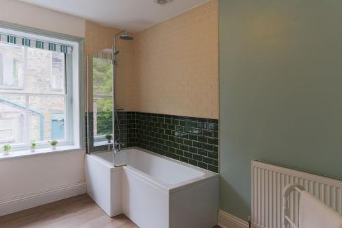 a bathroom with a bath tub and a window at The Manager's Suite in New Mills