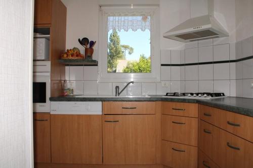 une cuisine avec des armoires en bois, un évier et une fenêtre dans l'établissement 602 - A ERQUY, jolie maison avec un grand jardin de 700m2 proche des plages sauvages, à Erquy