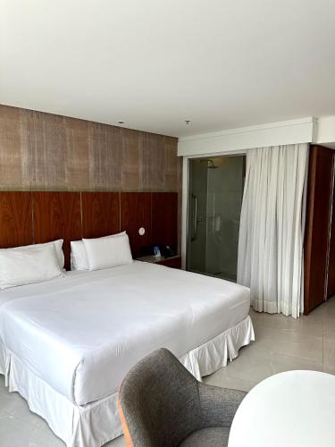 1 dormitorio con 1 cama blanca grande y 1 silla en Hotel Nacional RJ apto 504, en Río de Janeiro