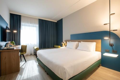 マルゲーラにあるBelstay Venezia Mestreの大きなベッドとデスクが備わるホテルルームです。