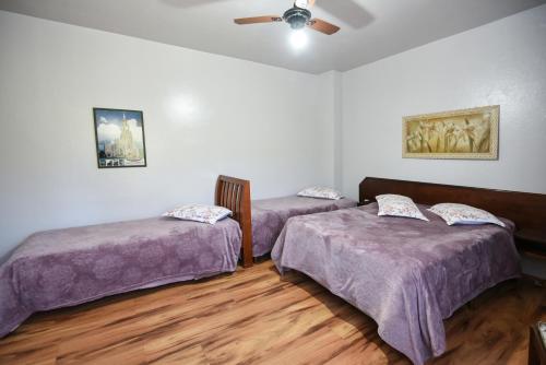 a room with two beds and a ceiling fan at Hotel Pequenino in Canela