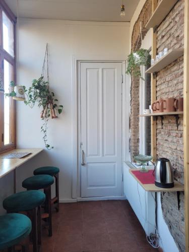 Friends Hostel في تبليسي: مطبخ مع باب أبيض وبعض الكراسي الخضراء