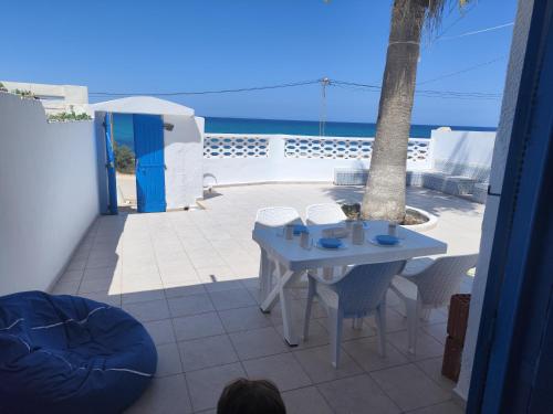 einen Tisch und Stühle auf einer Terrasse mit Meerblick in der Unterkunft Villa dar nina hergla in Harqalah