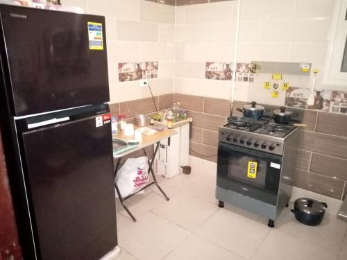 a kitchen with a black refrigerator and a stove at Cozy apartment At compound Dar Misr El Koronfil in New cairo