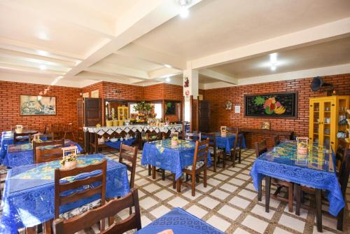 a restaurant with blue tables and chairs and a brick wall at Hotel Pequenino in Canela