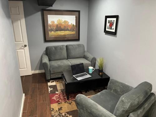 een woonkamer met een bank en een tafel met een laptop bij Plush garden level apartment near Stowe in Morristown