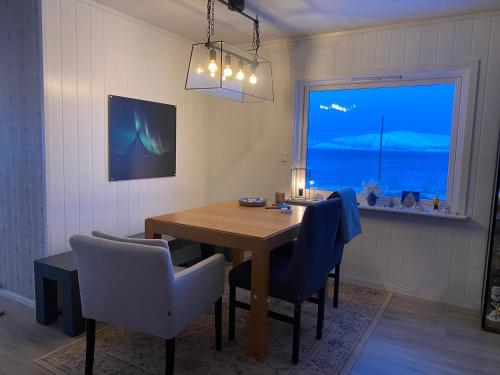 ein Esszimmer mit einem Tisch, Stühlen und einem Fenster in der Unterkunft Cozy cabin with amazing sauna house in Straumen