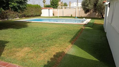 a backyard with a swimming pool and a grass yard at Montaraz 1 Espartinas in Espartinas