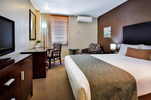 a hotel room with a bed and a flat screen tv at Madison Plaza Townsville in Townsville