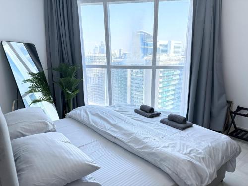 a bed with two towels on it in front of a window at Deluxe Apartment With Panoramic View Near Metro in Dubai