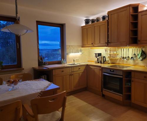 uma cozinha com armários de madeira, uma mesa e uma janela em FeWo Weitblick in Höhenlage von Greiz em Greiz