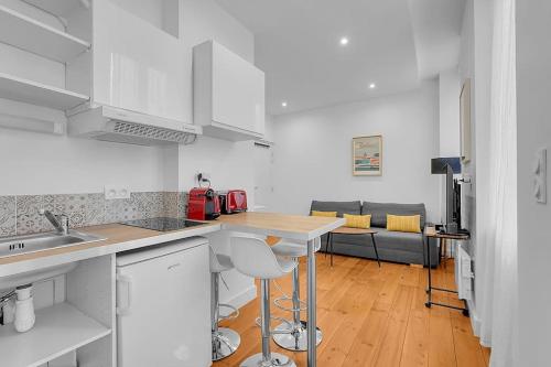 une cuisine avec des armoires blanches et un salon dans l'établissement Le Cocon - T2 Cosy hypercentre avec parking, à Toulouse