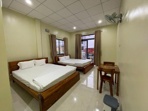 - une chambre avec 2 lits, une table et une fenêtre dans l'établissement Nhà nghỉ Hoa Dũng, à Hà Tiên