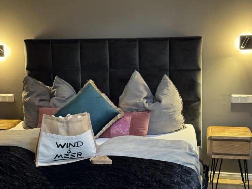 a bed with a black headboard with pillows on it at Gästehaus Wind und Meer in Norddeich