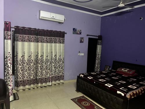 1 dormitorio con paredes moradas, cama y cortinas en Shiv mahima nivas, en Bareilly