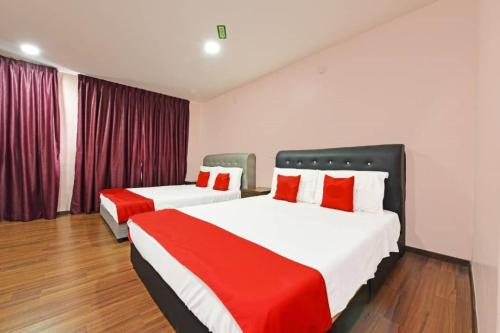 two beds in a hotel room with red and white at Seri Mawardah Hotel in Malacca