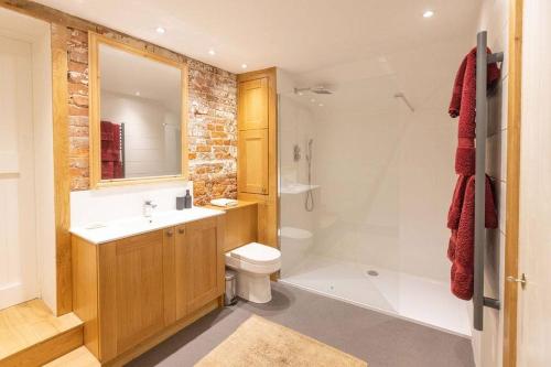 a bathroom with a sink and a toilet and a shower at The Granary - Wood Farm Barn. Luxury Barn with wonderful countryside views in Bawdeswell