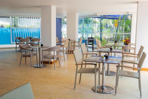 a dining room with tables and chairs and windows at HOTEL OCEANIA in Cartagena de Indias