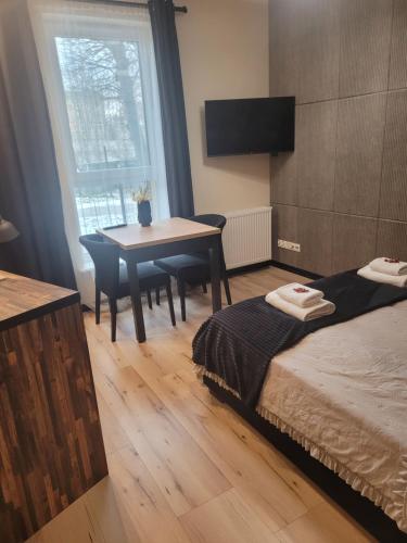 a bedroom with a bed and a table and a window at Apartament w sercu Elbląga in Elblag