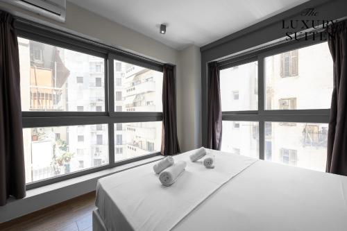 a bedroom with a white bed with large windows at WeStay Apartments, The Luxury Suites in Thessaloniki