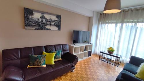 sala de estar con sofá de cuero marrón y TV en Guesthouse Metro Station en Matosinhos