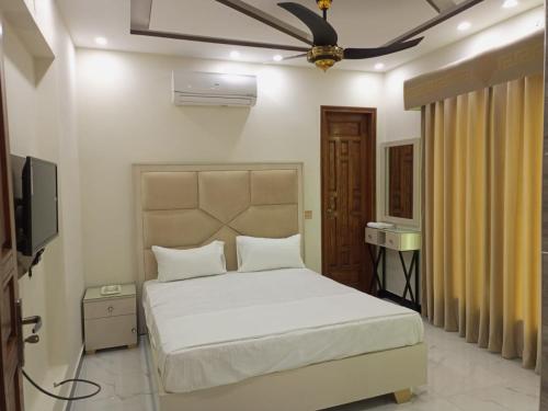 um quarto com uma cama branca e uma ventoinha de tecto em Dove Inn Family Residency Johar Town em Lahore