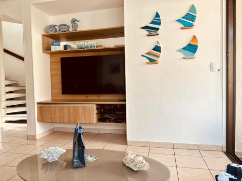 a living room with a tv and a table at Bangalô Boutique com piscina Privativa in Porto De Galinhas