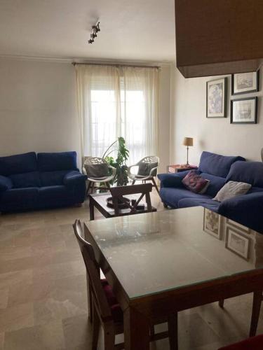 ein Wohnzimmer mit einem blauen Sofa und einem Tisch in der Unterkunft Piso 3 dormitorios en el centro in Cádiz