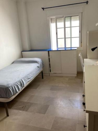 ein kleines Schlafzimmer mit einem Bett und einem Fenster in der Unterkunft Piso 3 dormitorios en el centro in Cádiz