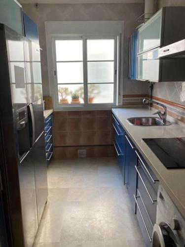eine Küche mit blauen Schränken, einem Waschbecken und einem Fenster in der Unterkunft Piso 3 dormitorios en el centro in Cádiz