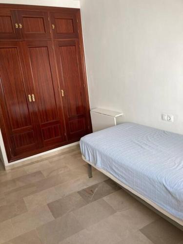 ein Schlafzimmer mit einem Bett und einigen Holzschränken in der Unterkunft Piso 3 dormitorios en el centro in Cádiz