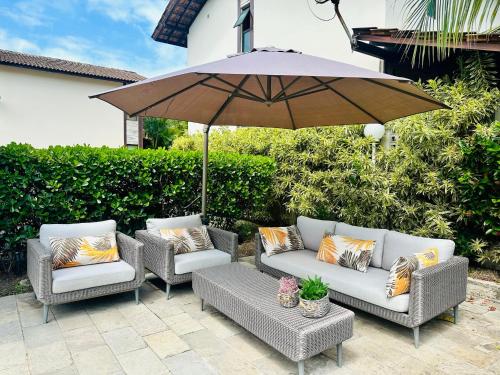 a patio with two chairs and an umbrella at Bangalô Boutique com piscina Privativa in Porto De Galinhas