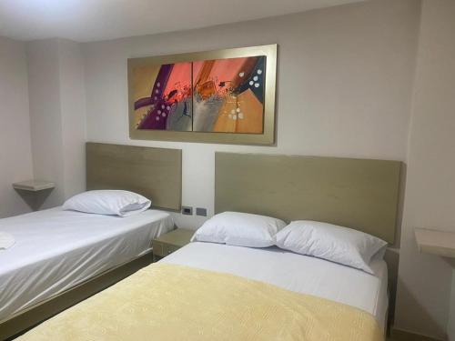 a room with two beds and a painting on the wall at HOTEL DASANTO HD in Barranquilla
