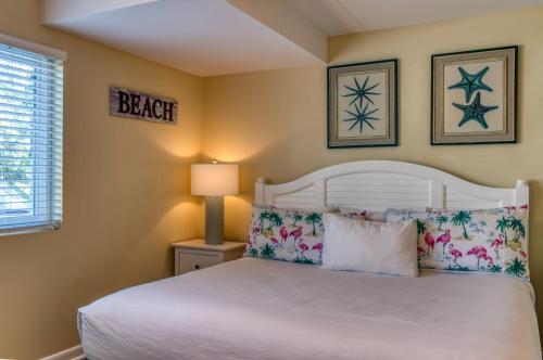 sypialnia z białym łóżkiem i 2 zdjęciami na ścianie w obiekcie The New Hotel Collection Beachfront w mieście Clearwater Beach
