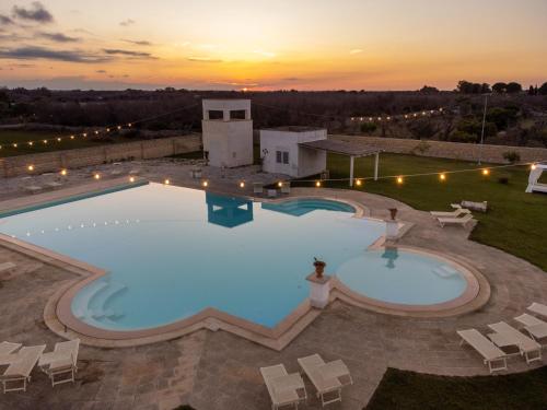 an overhead view of a pool with chairs and a sunset at Masseria Rauccio in Torre dell'Orso