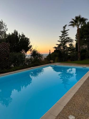 een blauw zwembad met een zonsondergang op de achtergrond bij Appartement studio in Nice