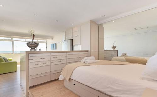 a white bedroom with a large bed and a kitchen at Sandringham 45 in Cape Town