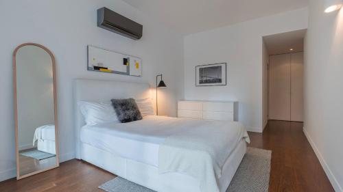 een witte slaapkamer met een wit bed en een spiegel bij Classy 3BDR Property by LovelyStay in Lissabon