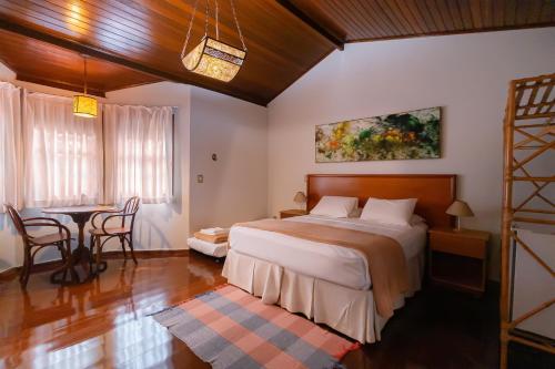 1 dormitorio con 1 cama, mesa y sillas en Pouso, Café e Cultura, en Pirenópolis