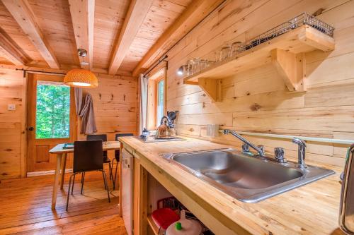 a kitchen with a sink in a log cabin at Huttopia Sutton in Sutton