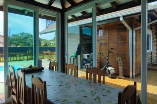 uma sala de jantar com mesa e cadeiras e uma grande janela em Deslumbrante Casa Frente Lagoa em Balneario Barra do Sul