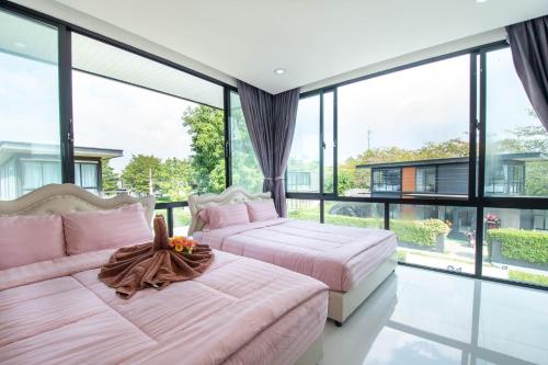 two beds in a room with large windows at 94 Pool Villa in Ban Huai Yai