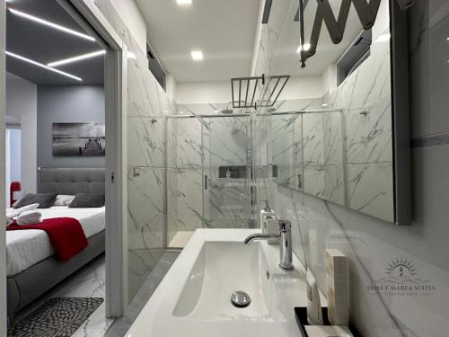 a bathroom with a sink and a shower and a bed at Dolce Marea Suites in Licata