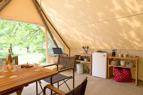 a tent with a table and chairs and a refrigerator at Huttopia Sutton in Sutton