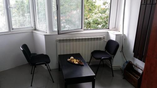 sala de estar con 2 sillas, mesa y 2 ventanas en Cozy Square, en Skopje