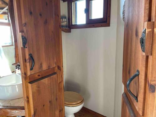 a bathroom with a wooden door and a toilet at Best View Romantic Cabin In Eco Village Klil in Clil