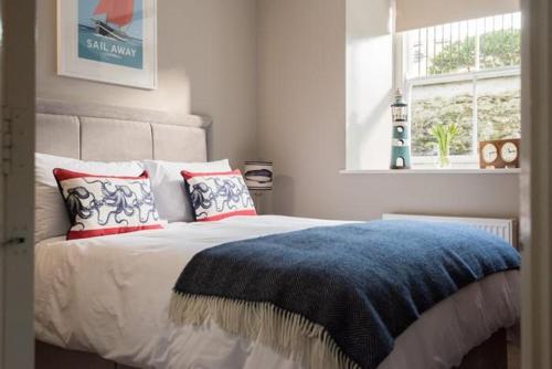 ein Schlafzimmer mit einem Bett mit einer blauen Decke und einem Fenster in der Unterkunft Stone's Throw - 2 Bed Apartment Centre of Falmouth in Falmouth