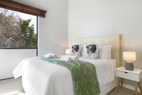 a white bedroom with a large white bed with a window at Links 2146 in Cape Town