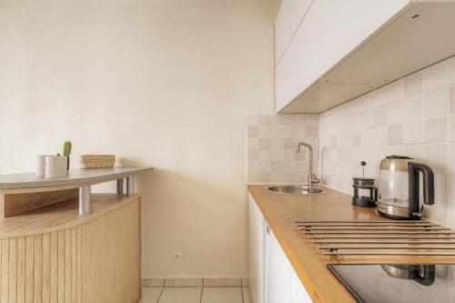a kitchen with a sink and a stove top oven at Le calme et cosy avec parking gratuit in Lyon